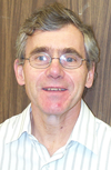 Portrait of a smiling man with grey hair and glasses.