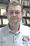 A man with glasses and a beard smiles, wearing a grey polo shirt with "NewfoundKing" on the left chest and a logo for "Newfoundland & Labrador" on the right.